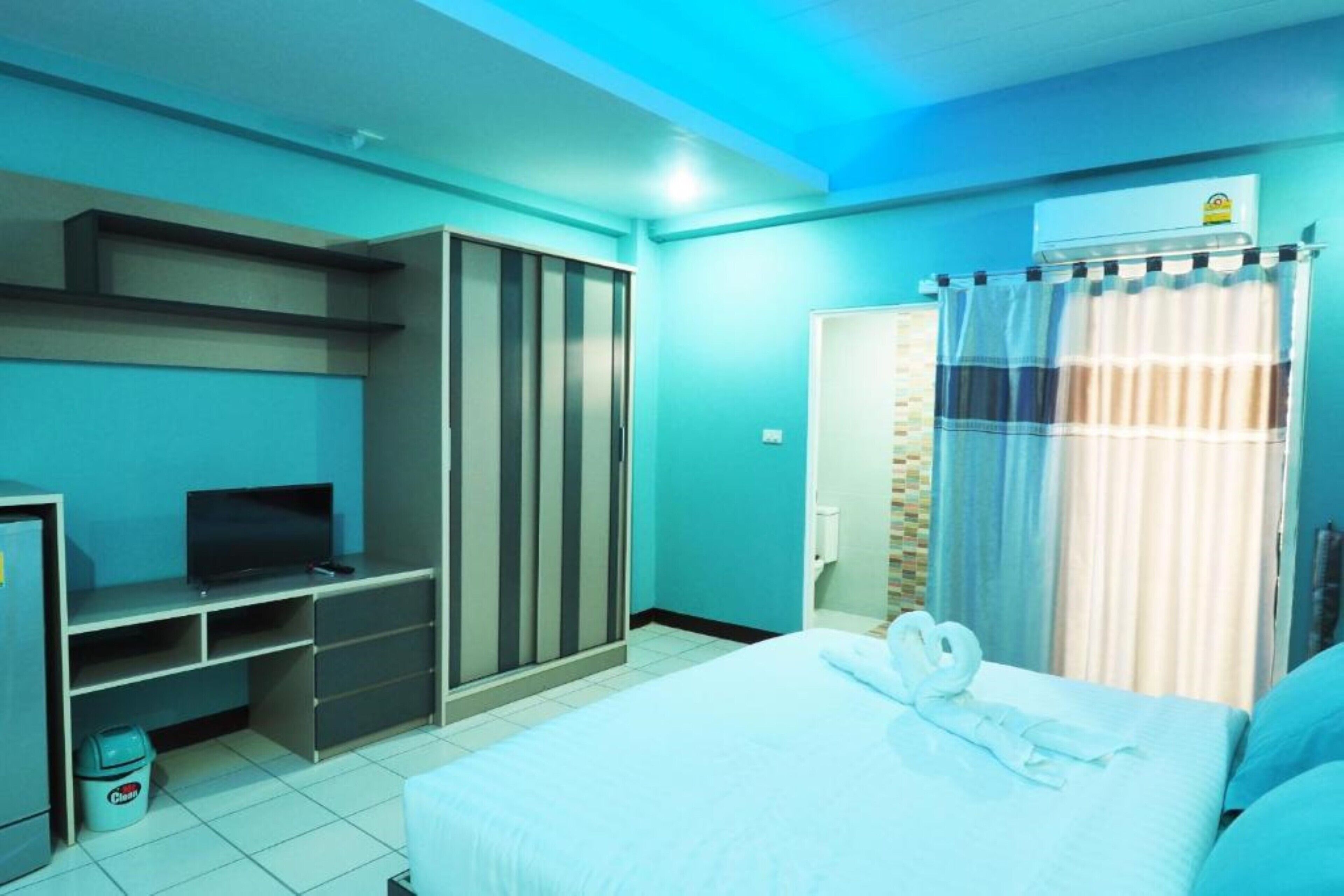 Una habitación de hotel con cama, televisor, armario y baño.