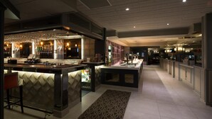 Un área de bar moderna con mostrador, asientos y una alfombra estampada.