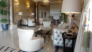 Un vestíbulo lujoso con muebles de alta gama, un gran candelabro y columnas decorativas.