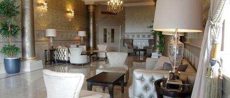 A luxurious lobby with high-end furniture, a grand chandelier, and decorative columns.