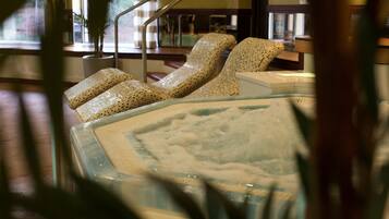 Unwind in a serene indoor space with a glass-enclosed hot tub and comfortable lounge chairs.