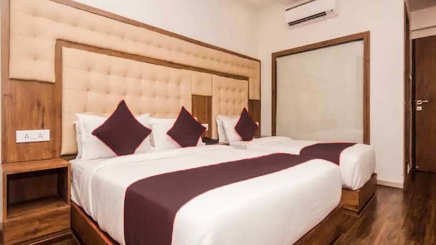 Une chambre d’hôtel avec un grand lit, une tête de lit en bois, un grand miroir et un plancher en bois.