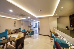 A hotel lobby with a reception desk, seating area with chairs and tables, and a kitchen area in the background. - The Meretto Hotel Laleli (Istanbul)