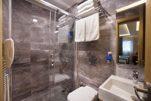 A modern bathroom with a glass-enclosed shower, a white sink, and a mirror reflecting a bedroom. - The Meretto Hotel Laleli (Istanbul)