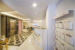 A hotel reception area with a reception desk, a digital screen, a wall-mounted information board, and a check-in counter. - The Meretto Hotel Laleli (Istanbul)