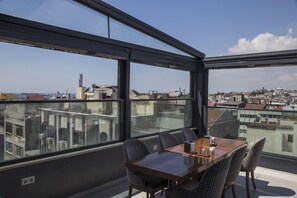 A modern dining area with a panoramic city view, large windows, and contemporary furniture.