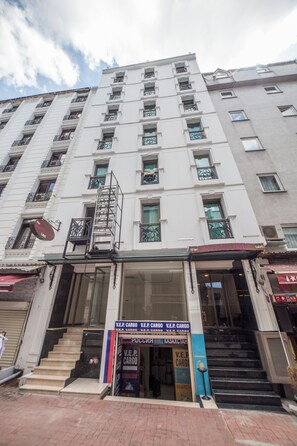 A multi-story hotel with a central staircase, a sign for 'V.E.P. Cargo' on the ground floor, and balconies with metal railings. - The Meretto Hotel Laleli (Istanbul)