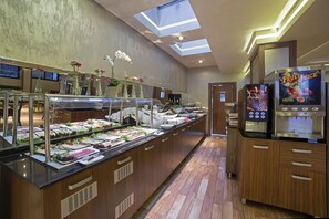 A buffet area with various food stations, a fruit juice dispenser, and a skylight.
