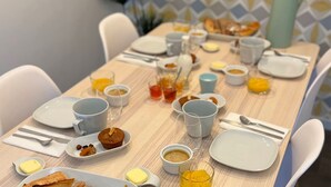 Ein gedeckter Frühstückstisch mit Tellern, Tassen und verschiedenen Speisen.