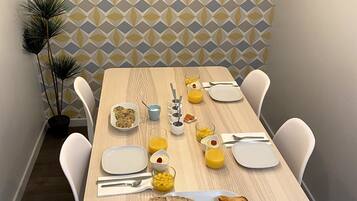 A dining table set with plates, cutlery, and food items, with a geometric patterned wall in the background.