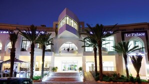 A hotel with a modern architectural design, featuring a central atrium with a staircase leading to the entrance. - Palm Djerba Suites (Mezraia)
