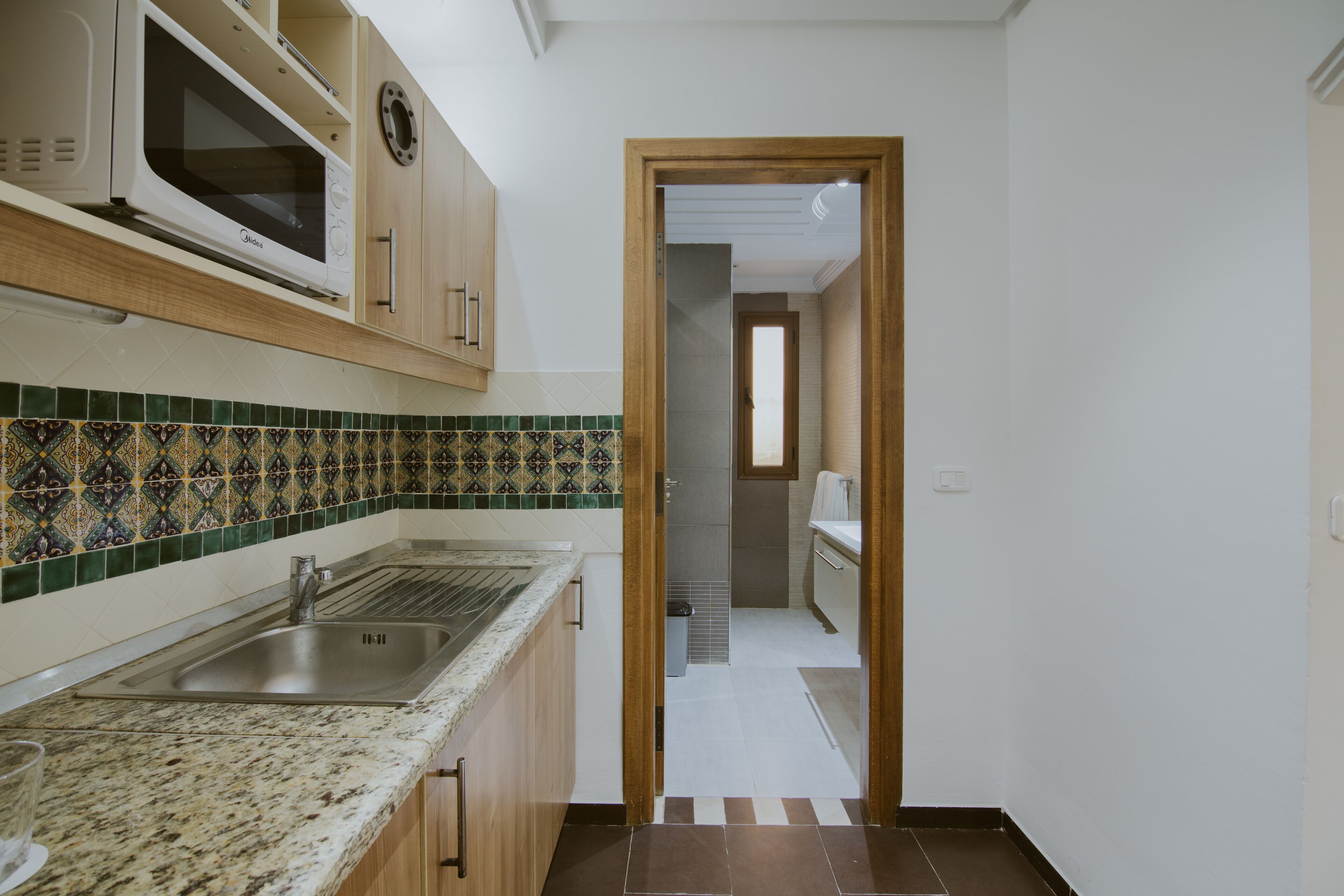 Una cocina con microondas, fregadero y un salpicadero decorado.
