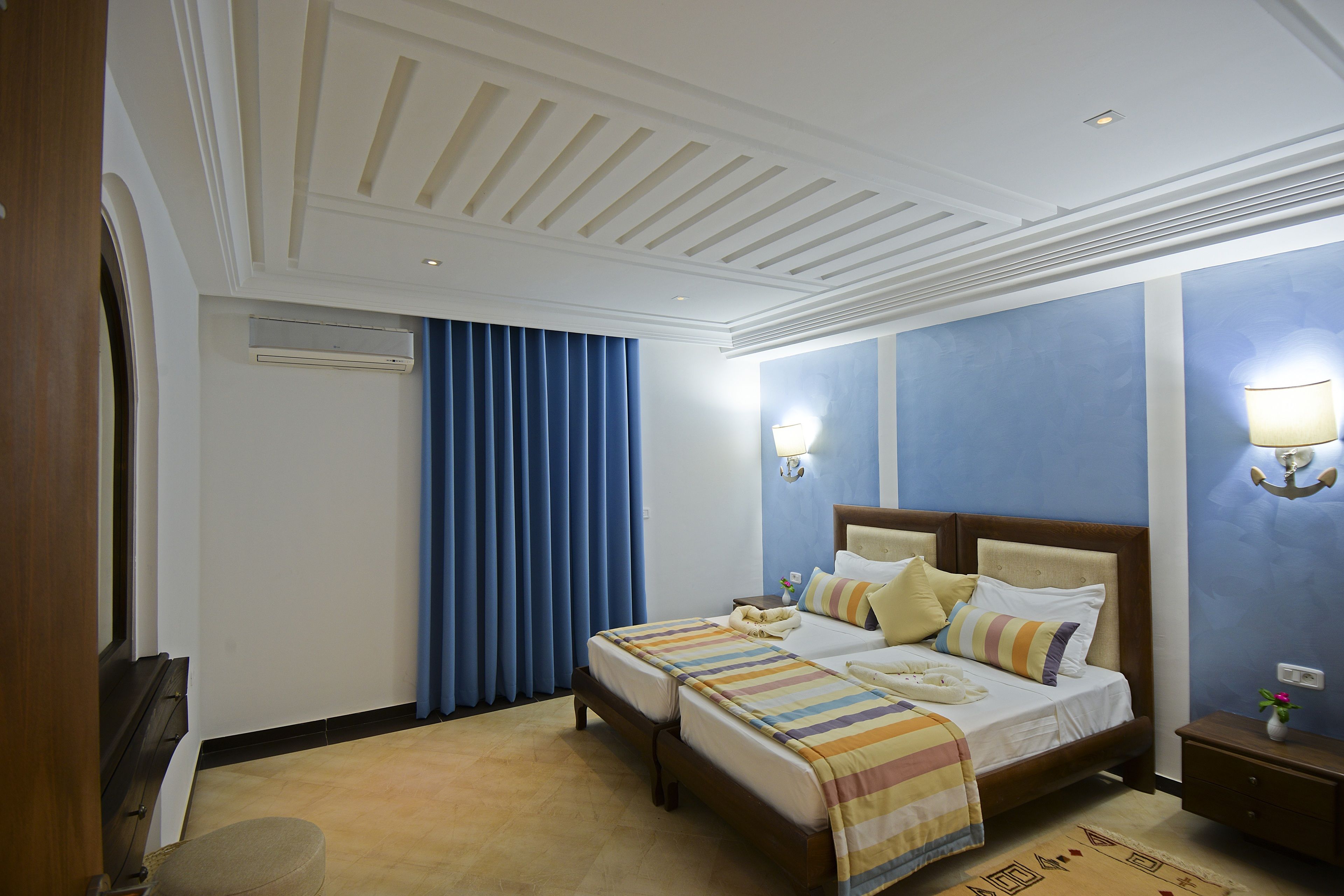 A hotel room with a large bed, two bedside tables, a nightstand, a desk, and a chair.