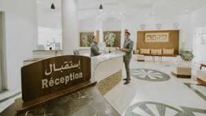 A reception area with a reception desk, a large mirror, and a seating area with sofas. - Palm Djerba Suites (Mezraia)