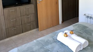 A bedroom with a bed, a TV on a wooden cabinet, and a wardrobe.