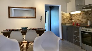 A modern kitchen with a built-in oven and a dining area with white chairs and a wooden table.