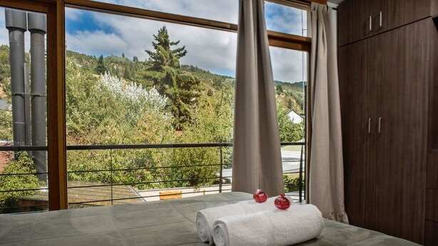 A room with a large window, a wooden wardrobe, and a rolled white towel on the floor.