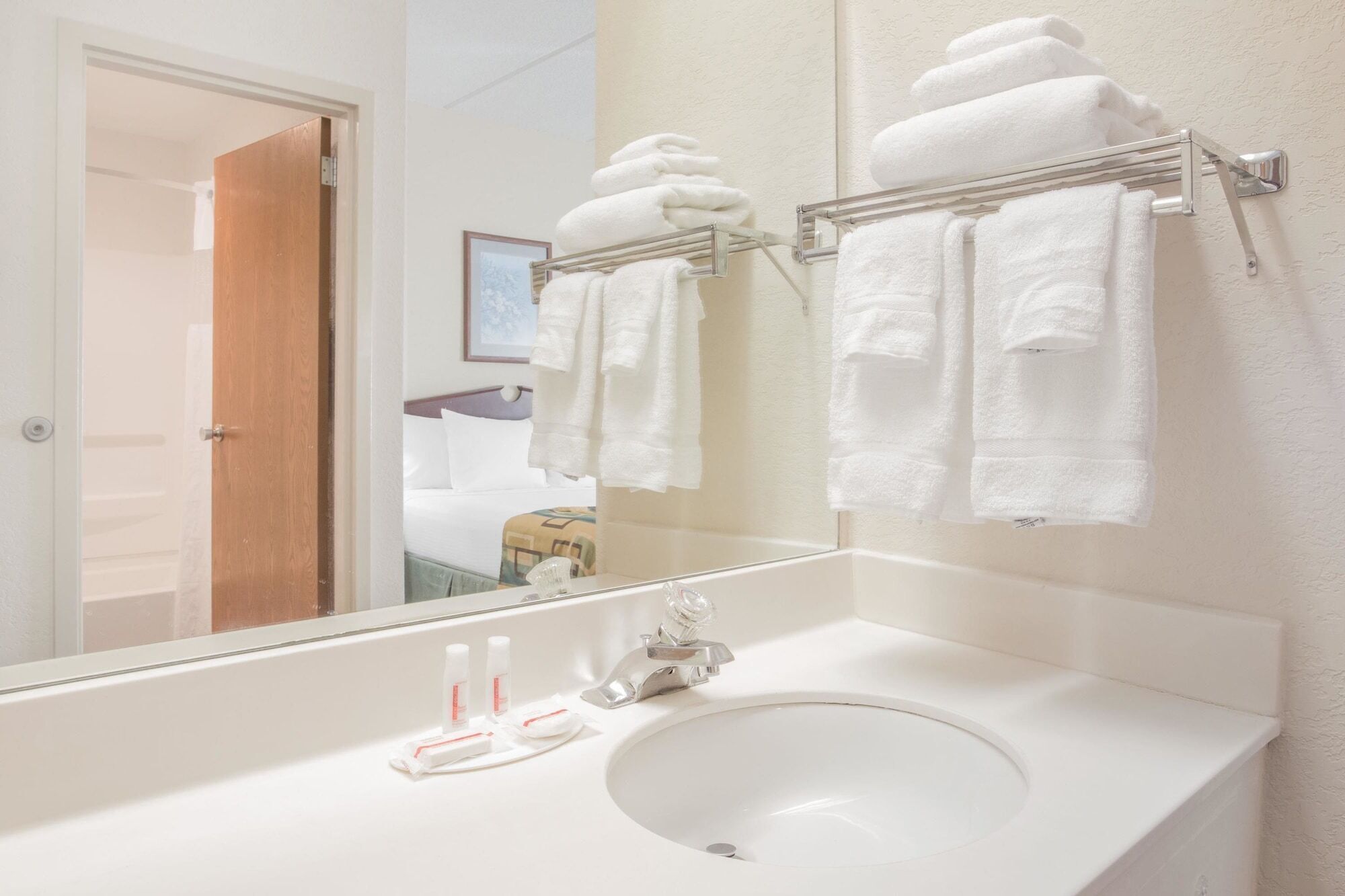 Un baño con lavamanos, espejo y toallero.