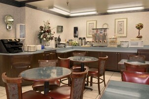 Una cocina moderna con una isla central, taburetes de bar y un comedor con mesas y sillas redondas.
