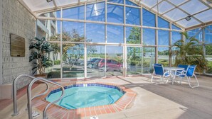 A covered pool area with a hot tub, seating, and a view of the outside. - Baymont Inn and Suites (Corbin)