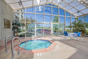 Zona de piscina cubierta con jacuzzi, asientos y vistas al exterior.
