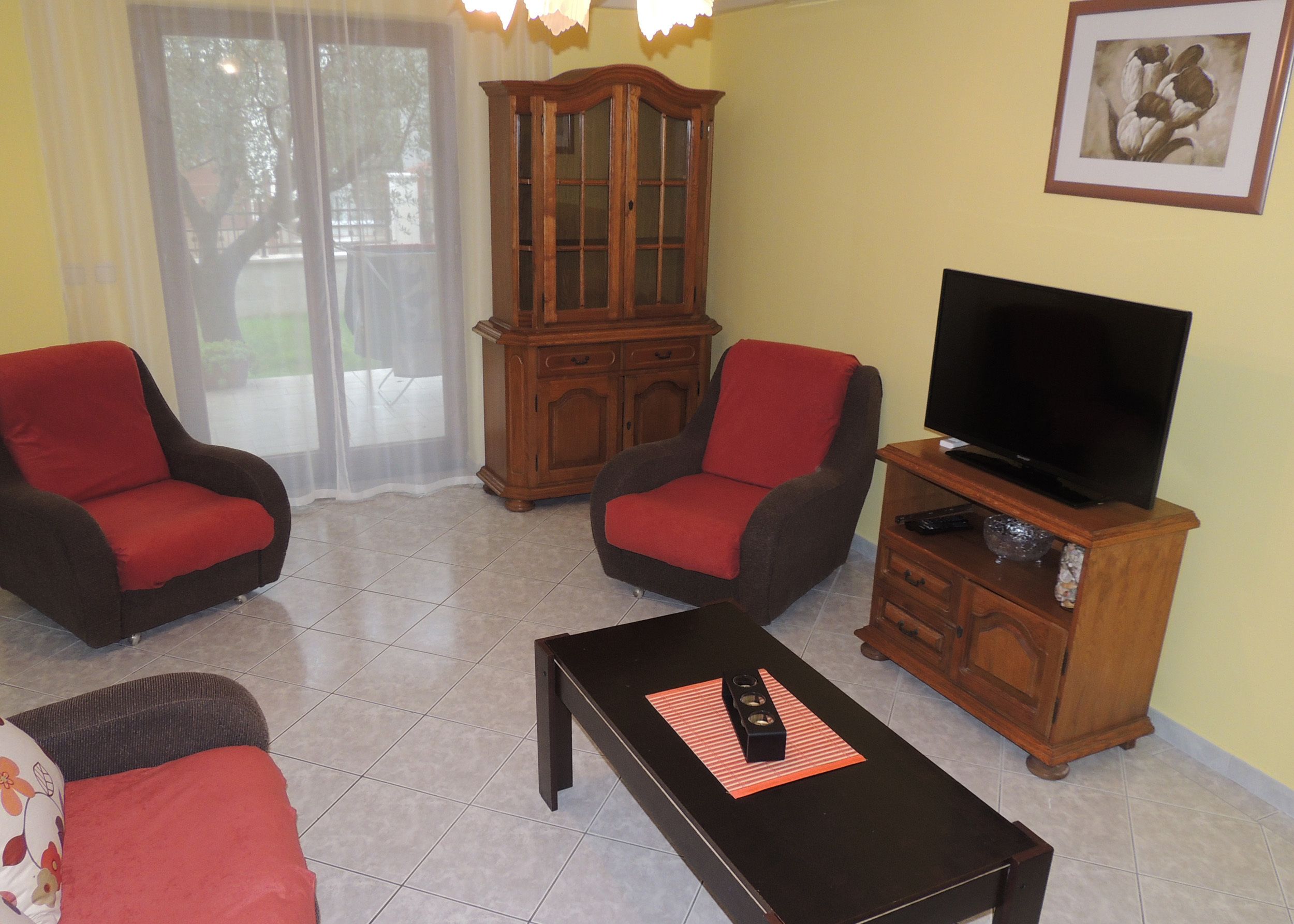 Una sala de estar con dos sillones, una mesa de centro, un televisor sobre un mueble de madera y un aparador.