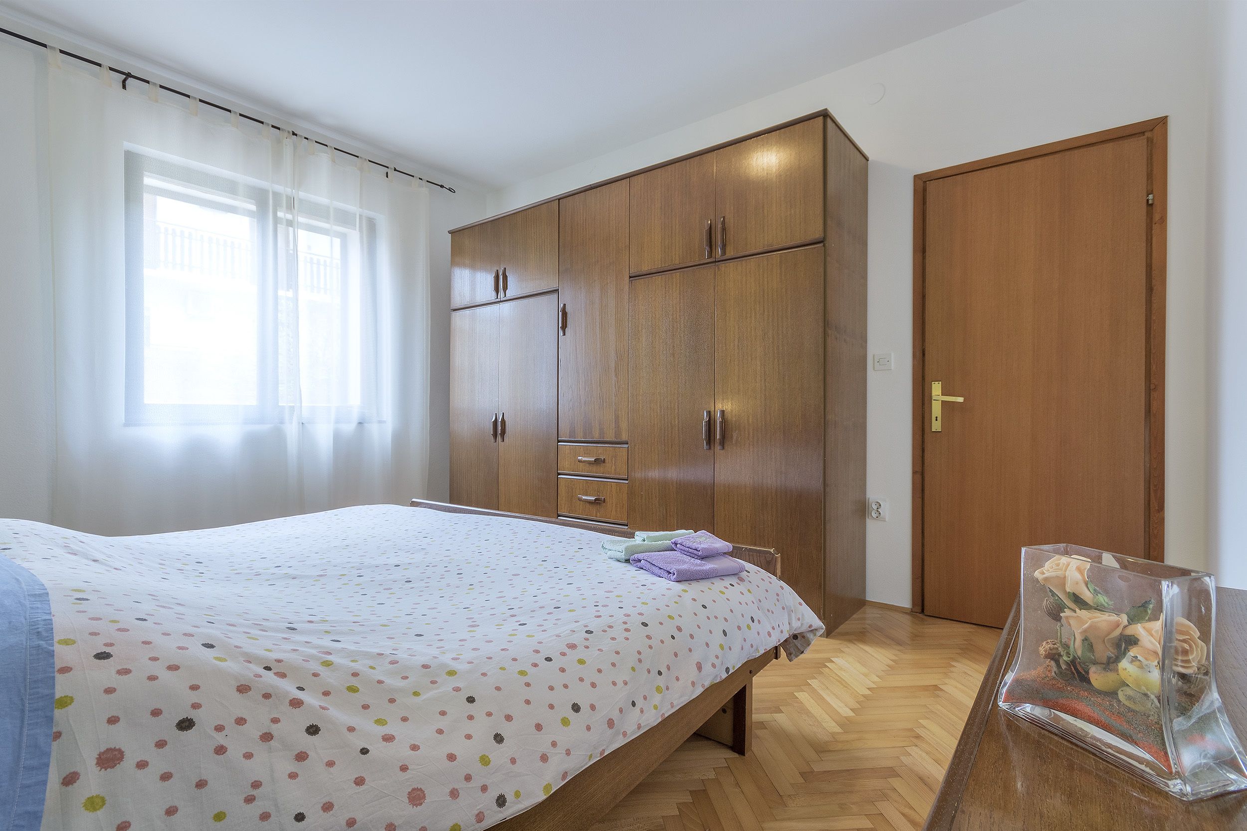 Ein Schlafzimmer mit einem Bett, einem Holzschrank und einer Tür.