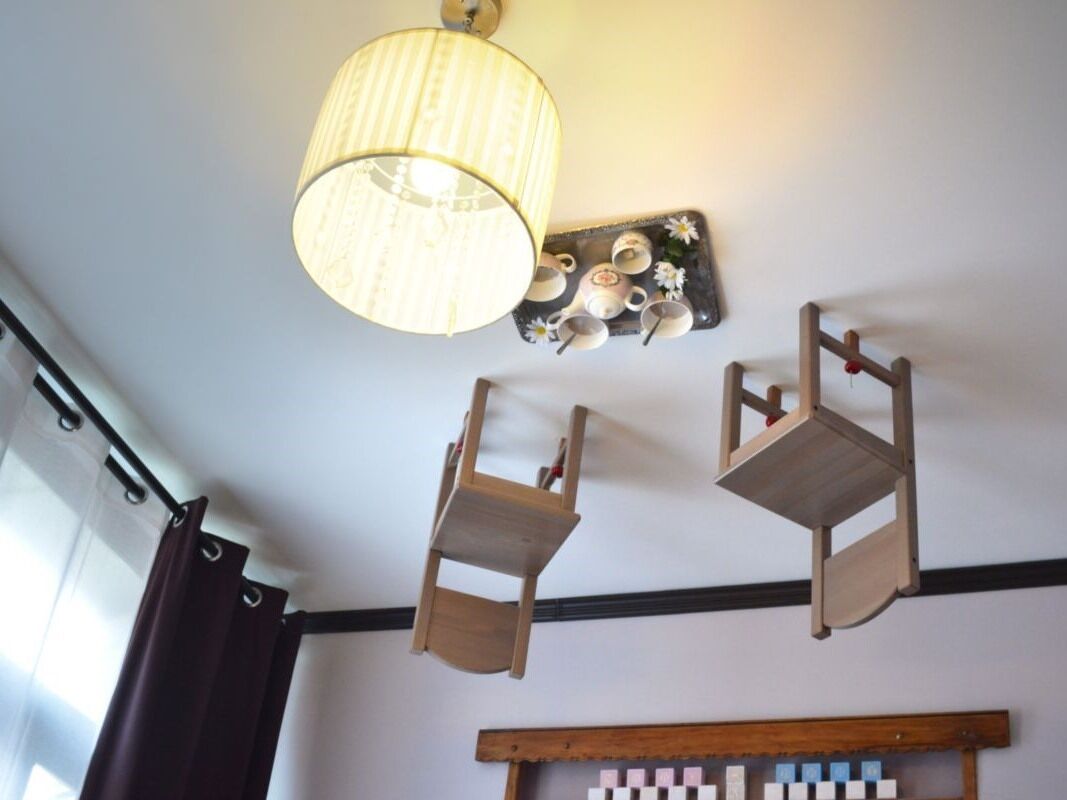 Una habitación con una silla colgante de madera, un estante de pared con tazas y platos, y un estante de madera con bloques.