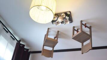 Una habitación con una silla colgante de madera, un estante de pared con tazas y platos, y un estante de madera con bloques.