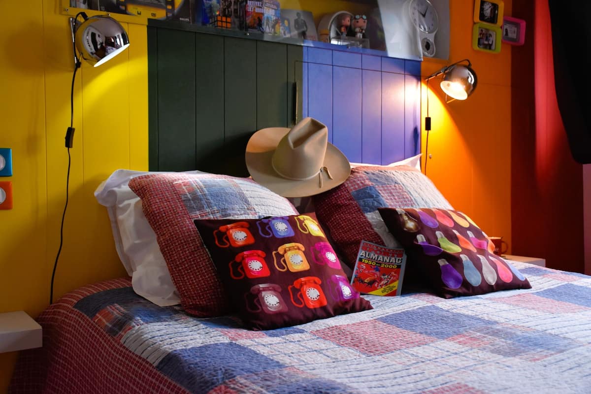 Una cama con colcha, un sombrero de vaquero y almohadas coloridas.