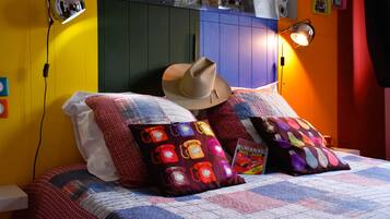 Una cama con colcha, un sombrero de vaquero y almohadas coloridas.