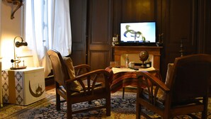 A traditional room with a television, wooden furniture, a patterned carpet, and a decorative lamp.