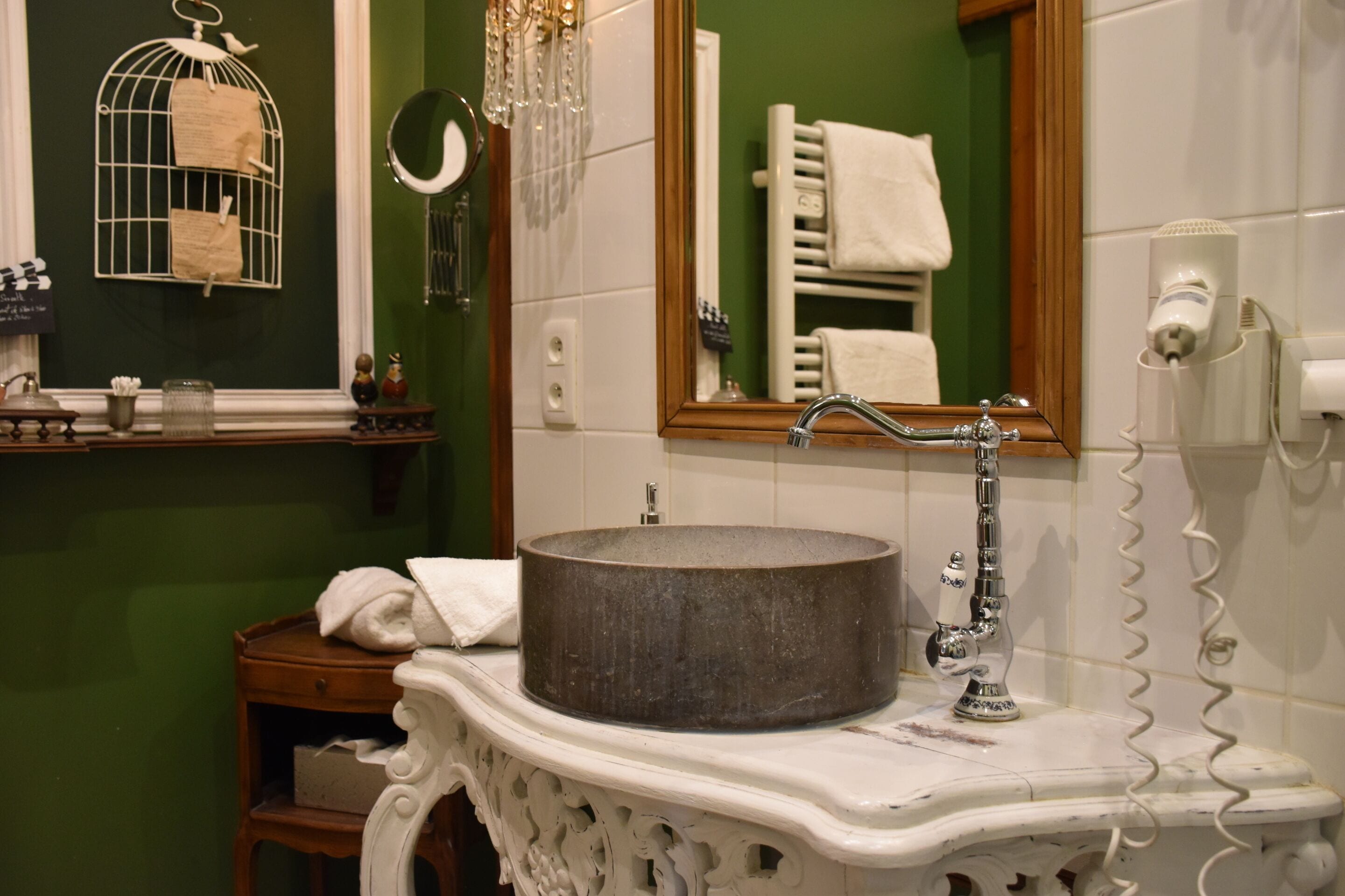 A bathroom with a round sink, a mirror, and a towel rack.