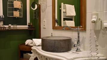 A bathroom with a round sink, a mirror, and a towel rack.