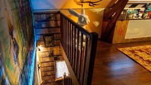 A staircase with a wooden railing leading to a landing with a bookshelf and a decorative wall.