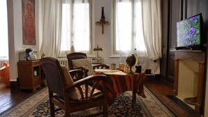 A traditional living room with a wooden sofa, a dining table, and a television.