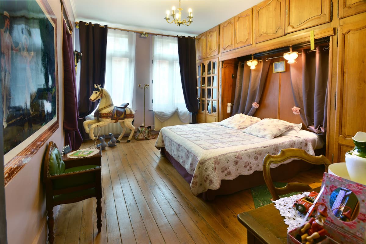 Una habitación tradicional con una cama de madera, una silla, una mesita y una figurita de caballo.