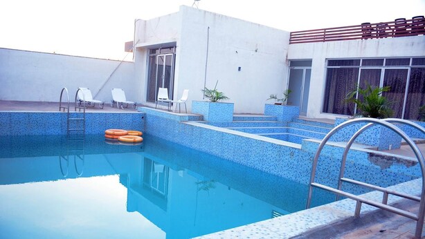 A swimming pool with a blue tiled edge, a ladder, and a few lounge chairs. - Wild Wadi Cottages Resort (Mendarda)