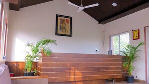 A reception area with a wooden bench, two potted plants, a ceiling fan, and a framed picture on the wall. - Wild Wadi Cottages Resort (Mendarda)