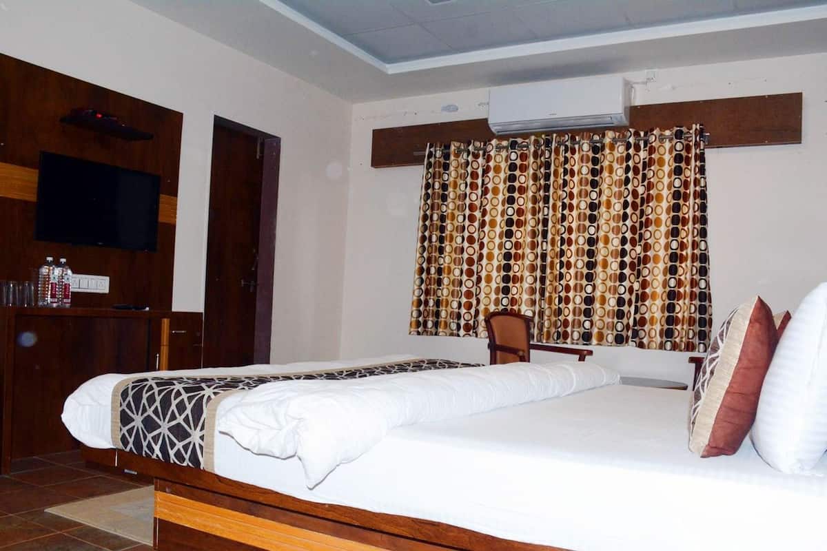 A hotel room with a bed, a television, a chair, and a curtain with a circular pattern.