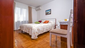 A bedroom with a bed, a chair, a nightstand, and a painting on the wall.