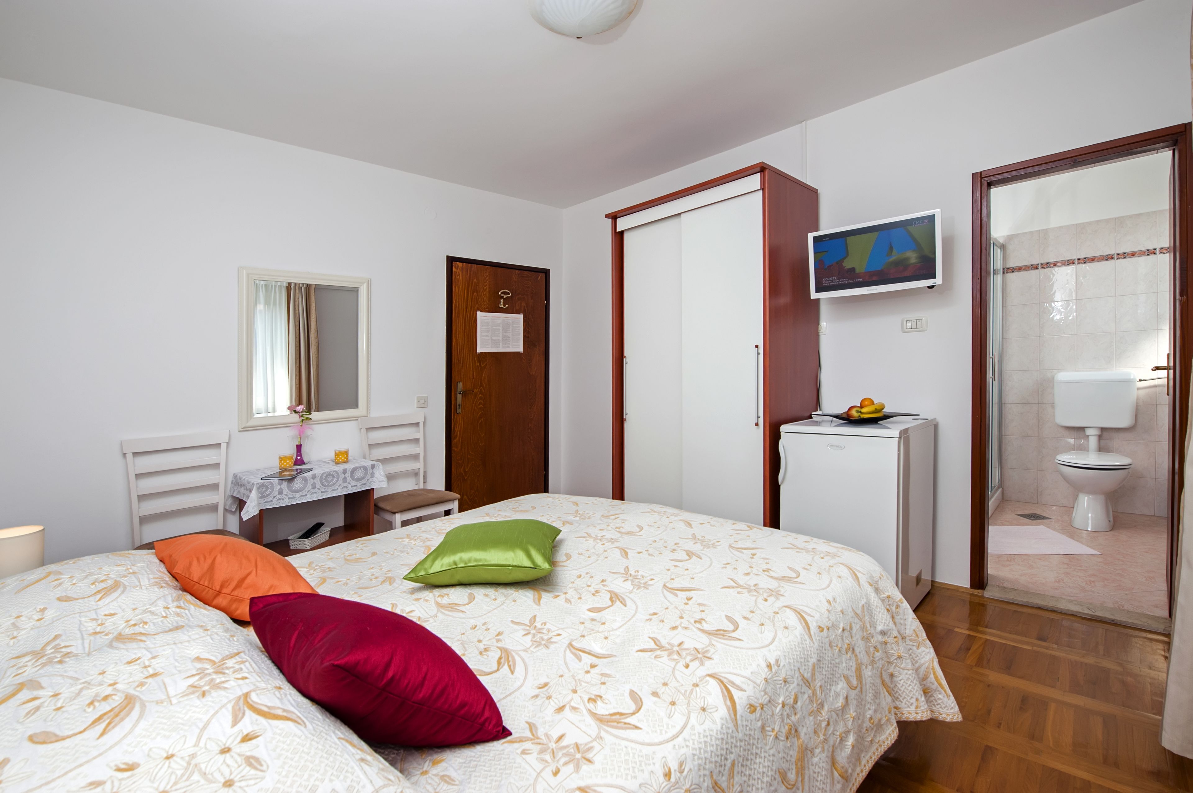 Une chambre à coucher comprenant un lit, un bureau, une télévision et une salle de bain.