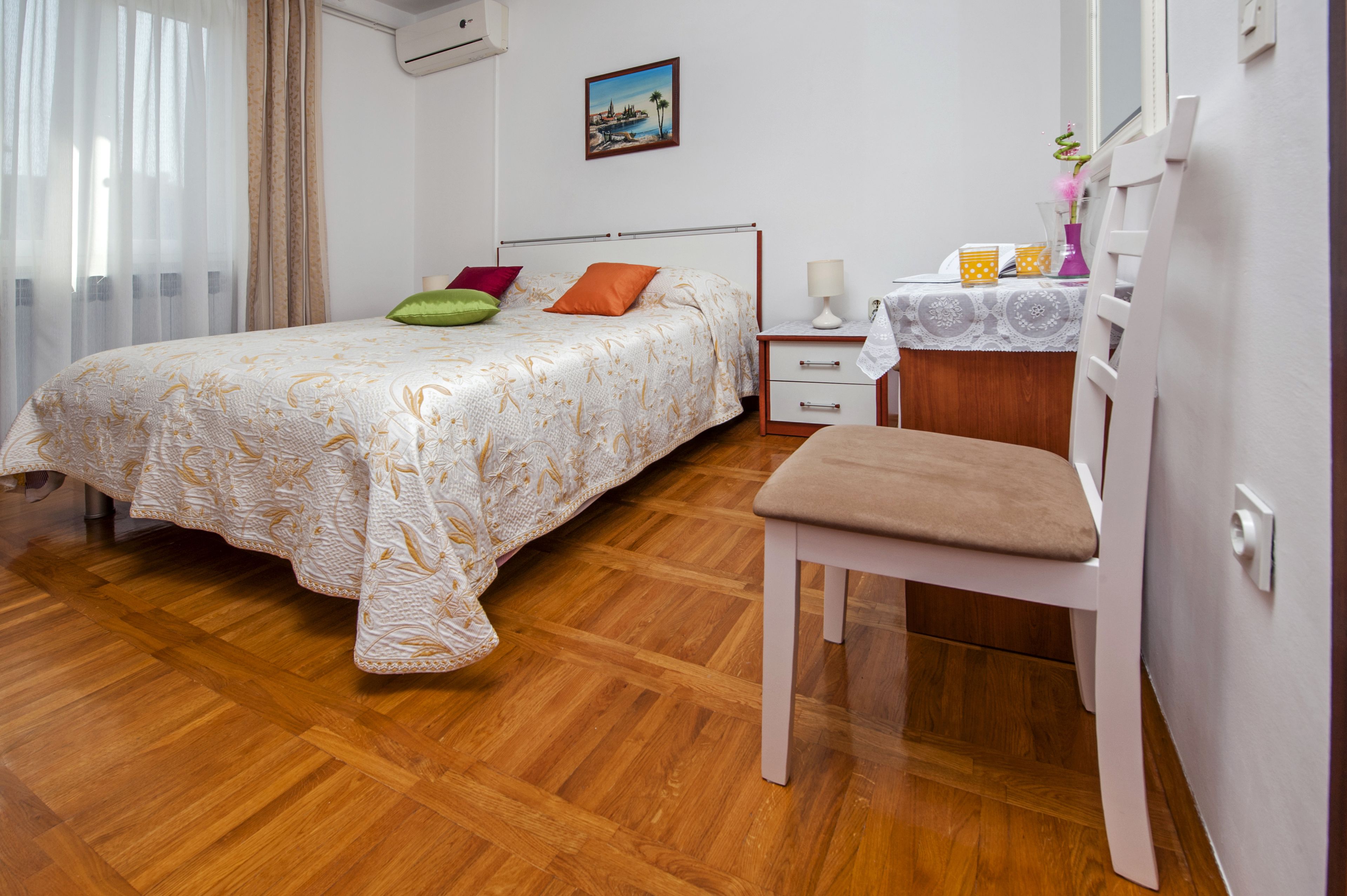 A bedroom with a bed, a chair, a bedside table, and a nightstand.