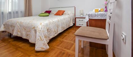 A bedroom with a bed, a chair, a bedside table, and a nightstand.