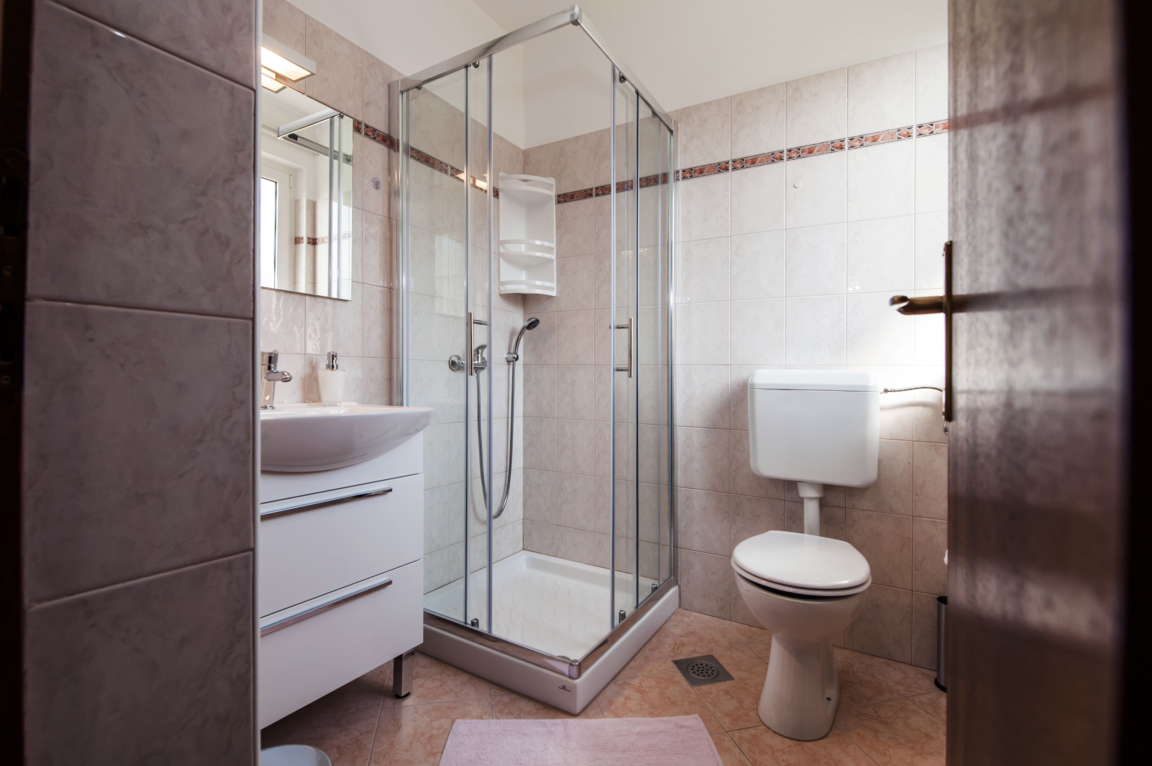 A modern bathroom with a glass-enclosed shower, a white sink, and a toilet.