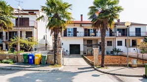A residential building with a gated entrance, palm trees, and a clear sky.