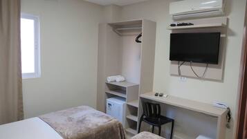 Habitación de hotel con dos camas, un escritorio, una silla, un televisor, un armario y un equipo de aire acondicionado.