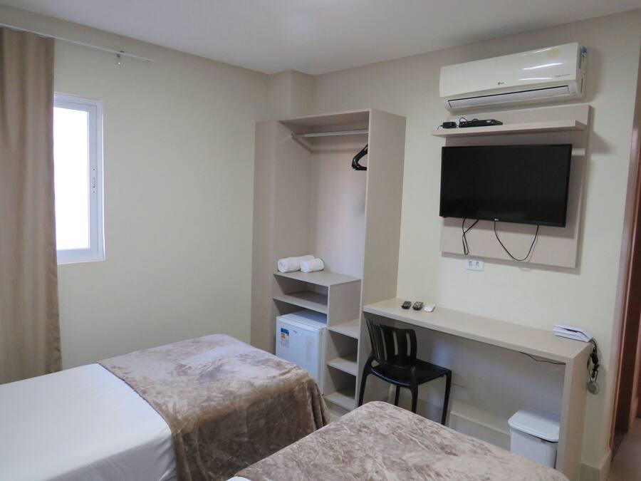 Hotelkamer met twee bedden, een bureau, een stoel, een televisie, een kledingkast en een airconditioning.