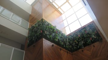 A high ceiling with a skylight, wooden paneling, and a green wall with plants.