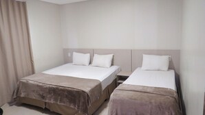 A hotel room with two beds, each with a headboard, a nightstand, and a curtain. - Hotel Sudoeste (Goiania)